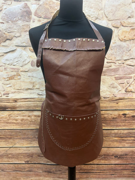 Vorderansicht einer braunen vintage Lederschürze mit Tasche, Nieten und Riemen.