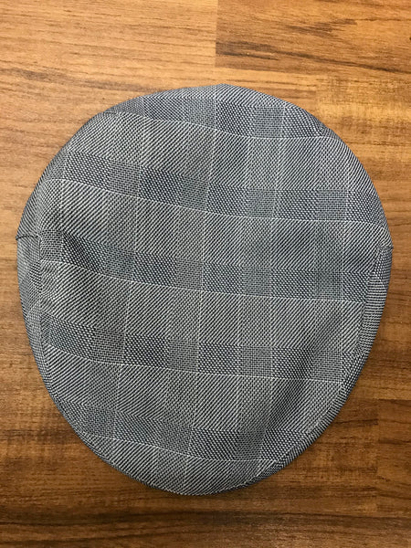 Graue Newsboy Cap im Karomuster, von oben fotografiert.