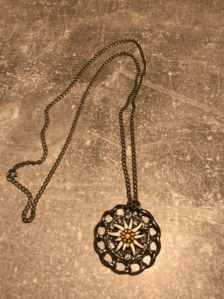 Vintage Trachtenkette mit großem Edelweiß-Anhänger in Silberoptik auf grauem Hintergrund.