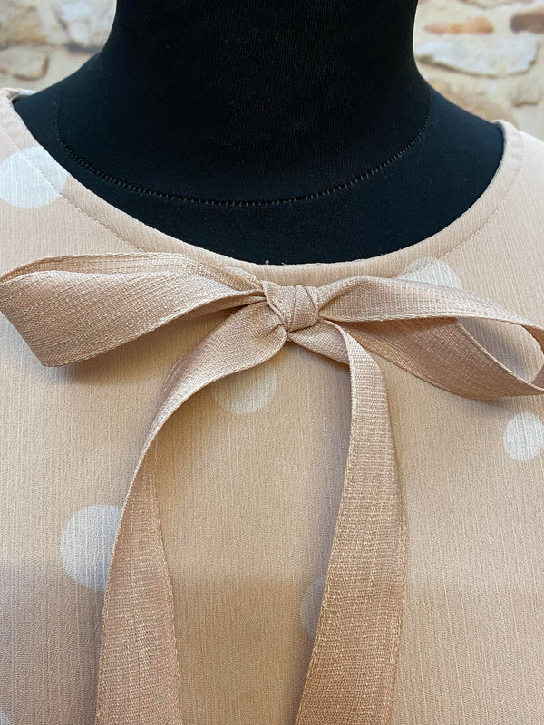 „Detail vom Ausschnitt mit roséfarbener Bindeschleife am gepunkteten 20er Jahre Kleid“