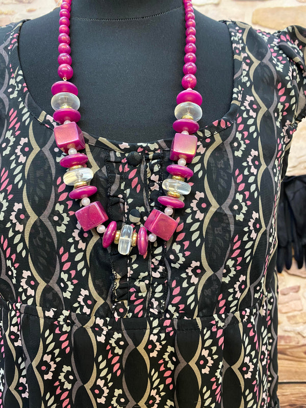 „Detailansicht vom Downton Abbey Kleid mit pinkfarbener Statement-Kette und dekorativem Ausschnitt“