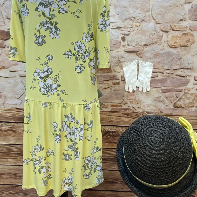 „Rückansicht vom gelben floralen Tageskleid im 1920er Jahre Stil mit Hut und weißen Handschuhen“