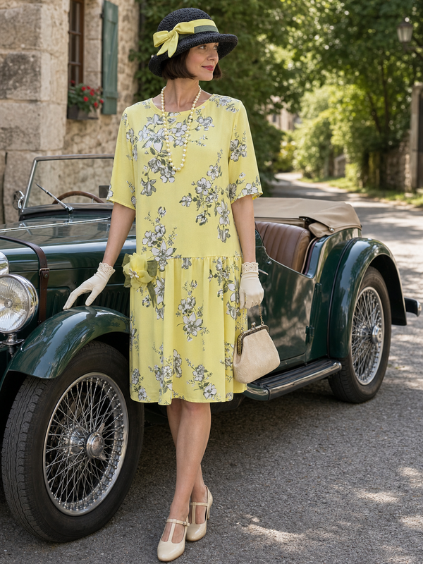 Model in gelbem 1920er Tageskleid Gr. 38 mit schwarzem Hut, Perlenkette und Handschuhen neben einem Oldtimer
