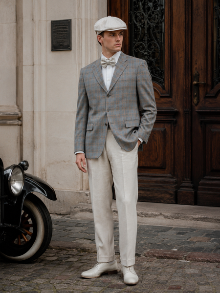 KI-generiert: 20er Jahre Herren Outfit mit grauem Karo-Sakko, heller Hose, Fliege und Schiebermütze im Vintage-Stil.