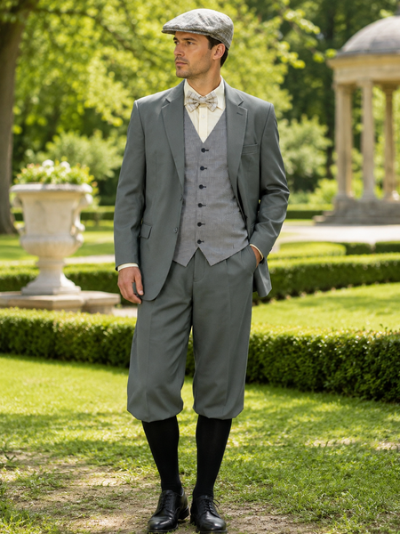 „Vintage Herren Sommerlook im 20er Jahre Stil mit graugrünem Anzug, Knickerbocker, Weste, Fliege und Schiebermütze vor grüner Parkkulisse“