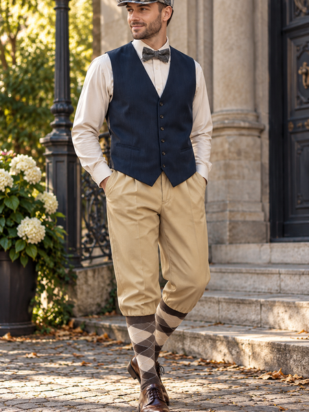 20er Jahre Herren Outfit mit dunkelblauer Weste, beiger Knickerbockerhose, Schiebermütze, Fliege und Kniestrümpfen am Model
