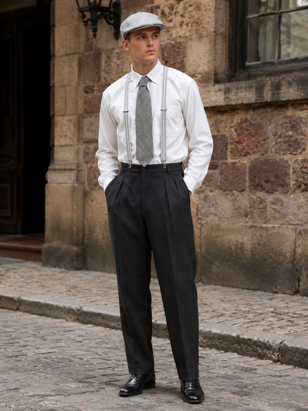 „20er Jahre Herren Outfit mit Schiebermütze, weißem Hemd, grauer Krawatte, Hosenträgern und dunkler Bundfaltenhose an männlichem Modell vor historischer Steinfassade“