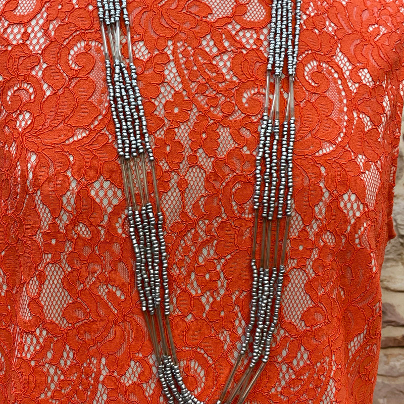 „Orangefarbenes Drop-Waist Kleid im 20er Jahre Stil mit langer mehrreihiger Vintage Kette“