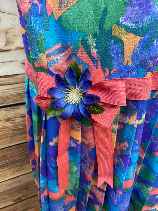 „Detailaufnahme 1920er Tageskleid im Drop Waist Stil mit pinker Schleife und blauer Blüte“