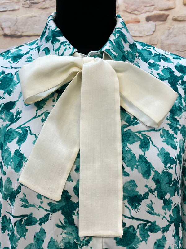 „Detailaufnahme 1920er Tageskleid mit großer cremefarbener Schleife und grünem Blumenmuster“