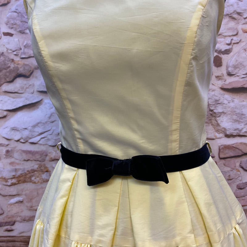 „Detailansicht vom hellgelben Swing Kleid im 50er Jahre Stil mit schwarzem Samtgürtel und Schleife“