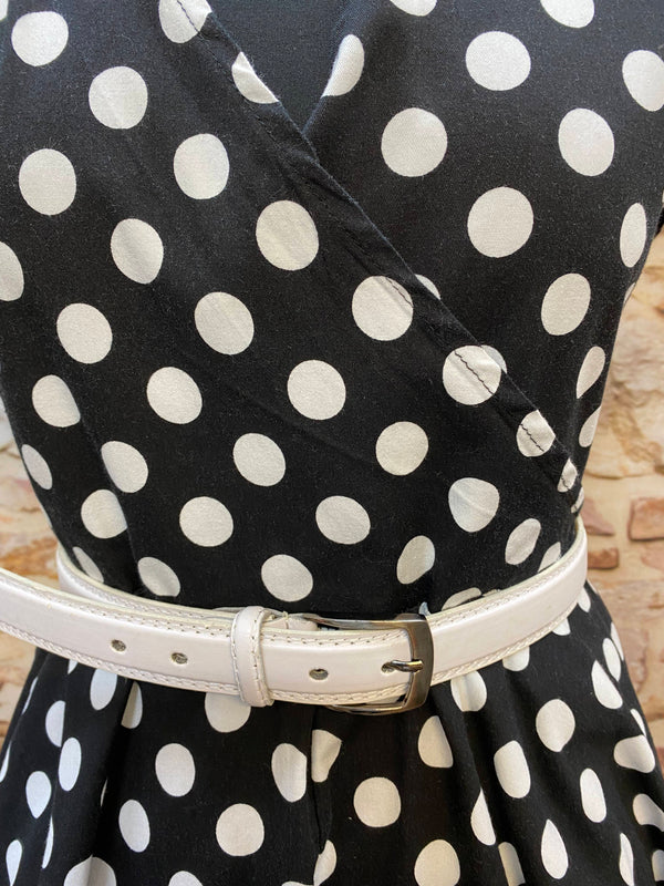 „Detailansicht vom gepunkteten 50er Jahre Kleid mit Wickeloptik-Ausschnitt und weißem Taillengürtel“