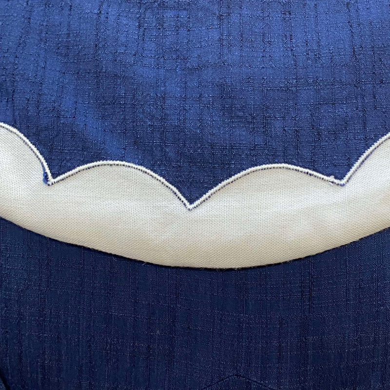 „Detailansicht vom 50er Jahre Vintage Matrosenkleid in Blau Weiß mit geschwungenem cremeweißem Ausschnittbesatz“