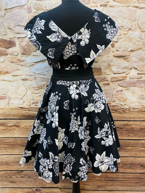 „Rückansicht vom 50er Jahre Kleid schwarz weiß mit Früchteprint und ausgestelltem Rock“