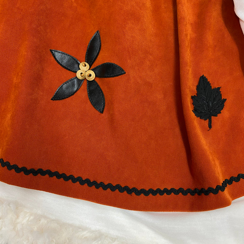 „Vintage 1970er Outfit mit gemusterter Schlaghose und orangefarbener Bluse“