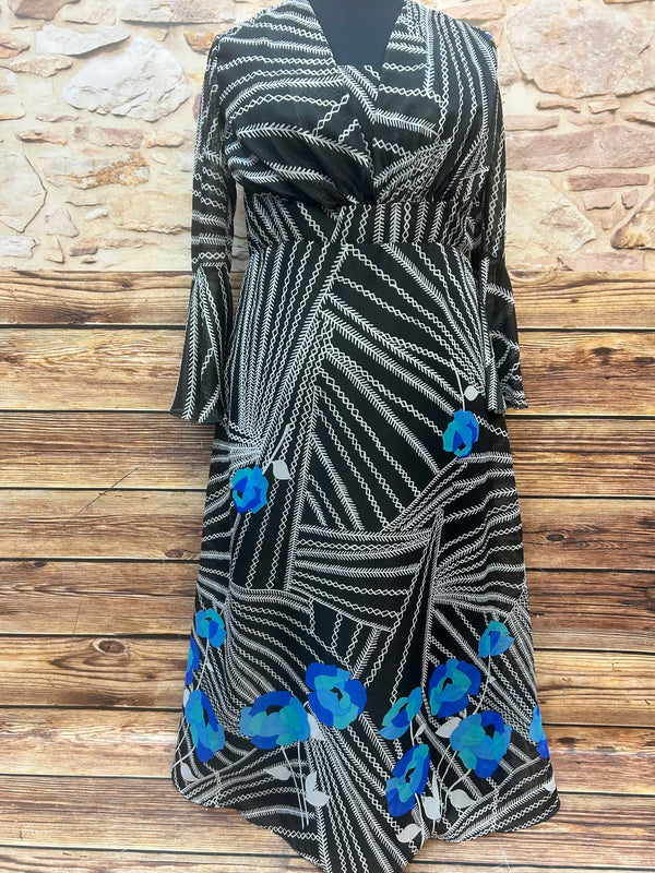 „Vintage Maxikleid 70er Jahre in Schwarz mit weißem Grafikmuster und blauen Blumen, Vorderansicht auf Puppe“