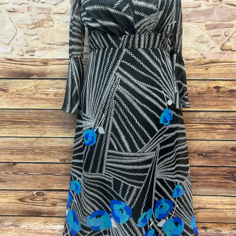 „Vintage Maxikleid 70er Jahre in Schwarz mit weißem Grafikmuster und blauen Blumen, Vorderansicht auf Puppe“
