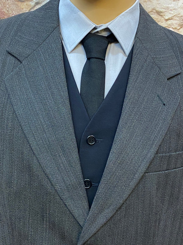 „Detail: Revers des grauen Schurwoll-Sakkos mit schwarzer Seiden-Strickkrawatte“