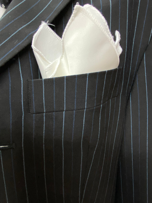 „Detail: weißes Einstecktuch in der Brusttasche des Nadelstreifen-Sakkos“
