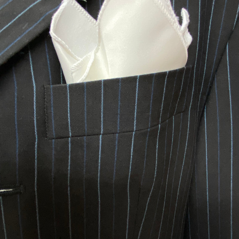 „Detail: weißes Einstecktuch in der Brusttasche des Nadelstreifen-Sakkos“