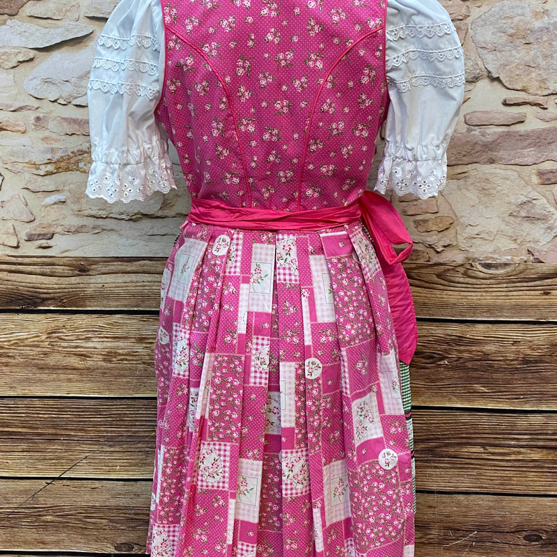 „Rückansicht des pink-grünen Dirndls mit Bindeschürze und floralem Muster“