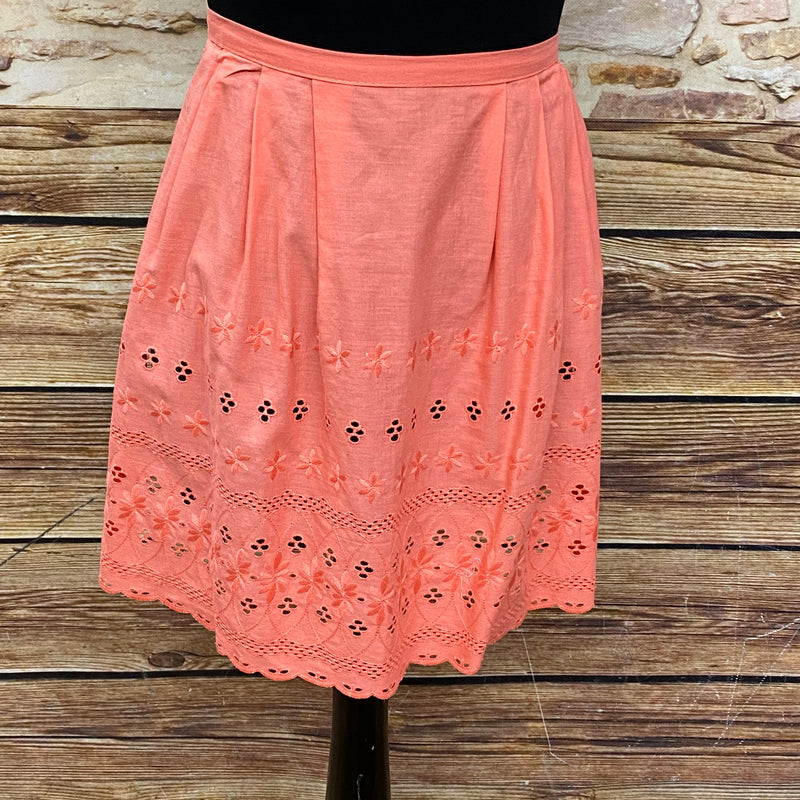 Lachsfarbene Vintage Dirndl-Schürze für Damen mit Lochmuster, Schürzenschließe und kurzer Passform aus Baumwolle, sehr guter Zustand.