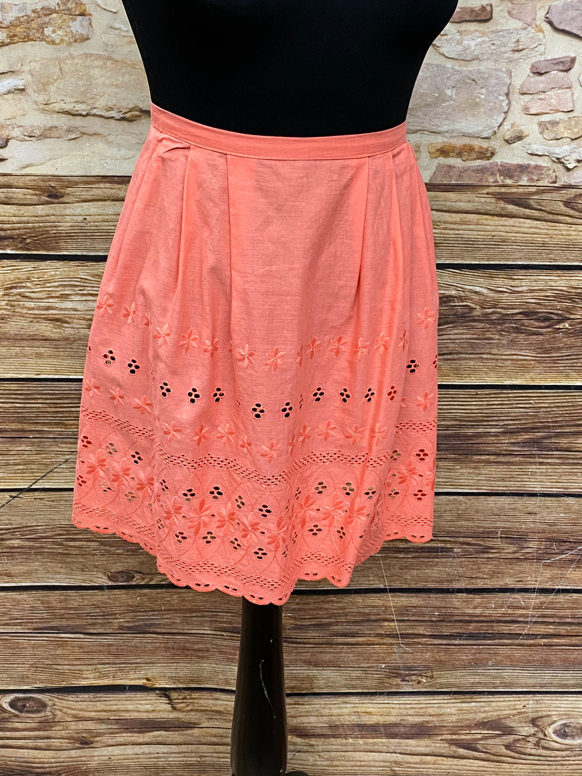 Lachsfarbene Vintage Dirndl-Schürze für Damen mit Lochmuster, Schürzenschließe und kurzer Passform aus Baumwolle, sehr guter Zustand.