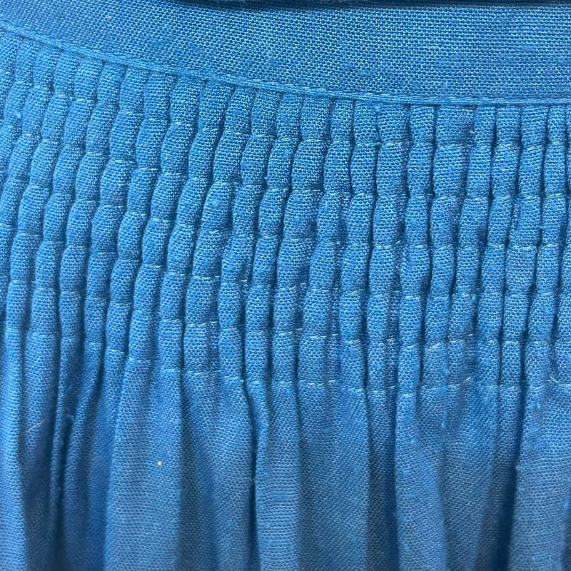 „Detail des gesmokten Bundes einer blauen Trachtenschürze aus Leinenmix“