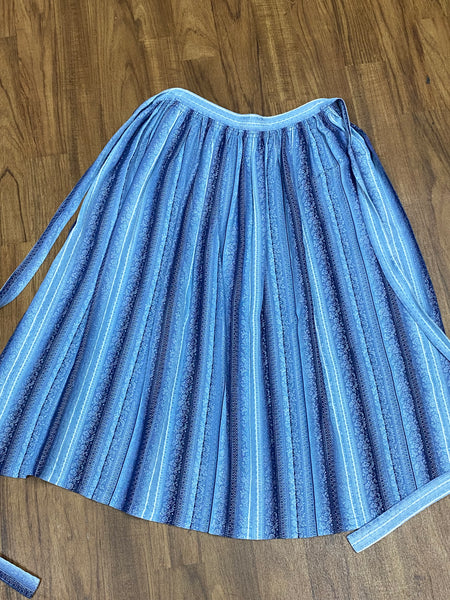 Blau gestreifte Vintage Dirndl-Schürze mit weißen und hellblauen Blumenranken, 68 cm lang, Baumwoll-Mischgewebe, Schleifenverschluss, sehr guter Zustand.