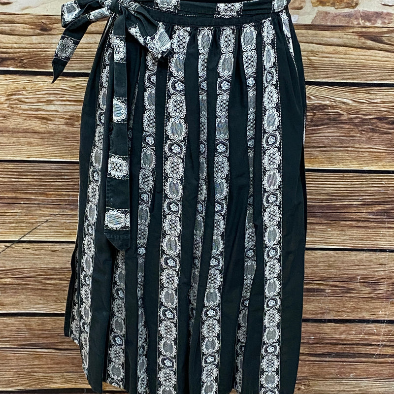 Schwarze Vintage Dirndl-Schürze für Damen mit weißen Ranken, 63 cm lang, aus Baumwoll-Mischgewebe, Schleifenverschluss, sehr guter Zustand.