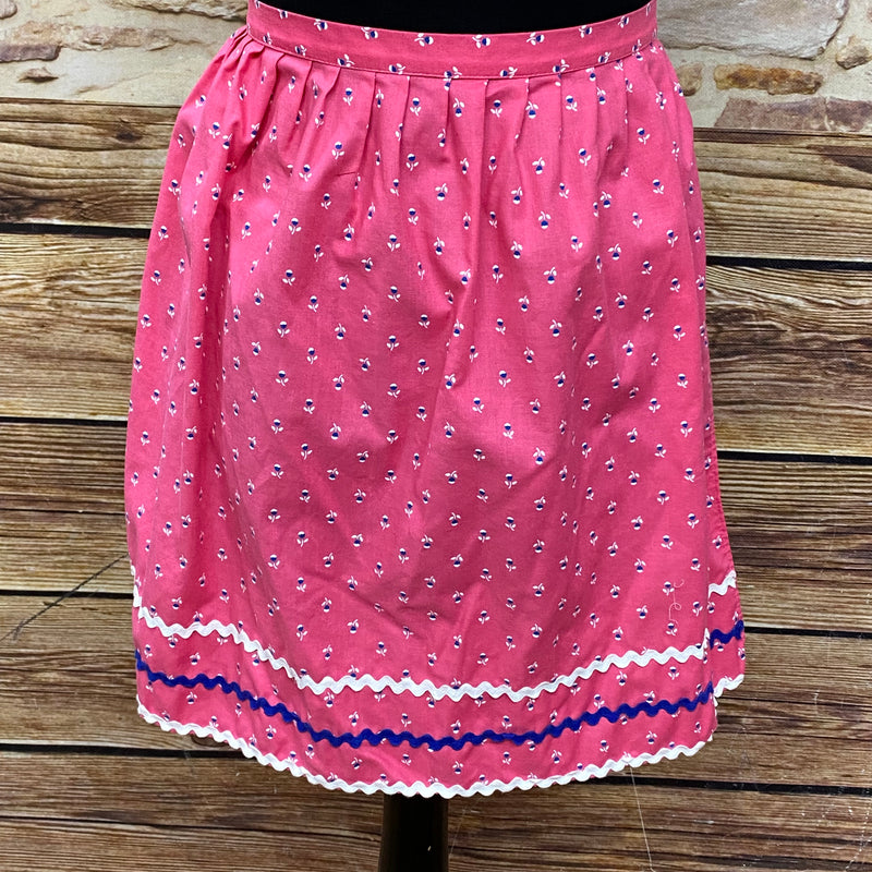 „Rosa Vintage Dirndl-Schürze  mit Blumenmuster, Zierborten in Weiß und Blau, Baumwolle, Schleifenverschluss.“