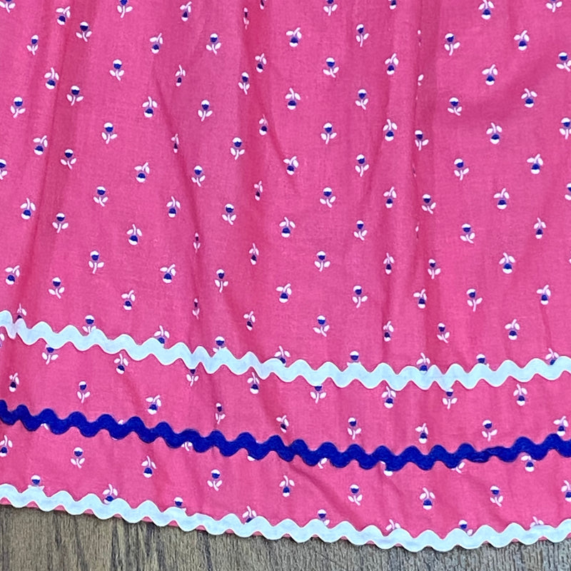 „Nahaufnahme, Rosa Vintage Dirndl-Schürze  mit Blumenmuster, Zierborten in Weiß und Blau