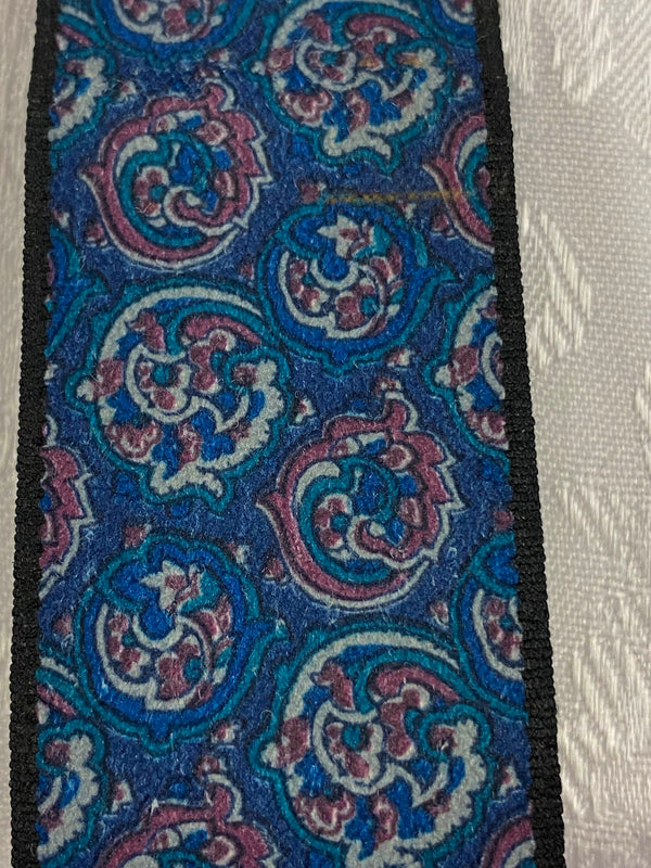 „Detailaufnahme von gemusterten Vintage Hosenträgern mit blauem Paisley-Muster“