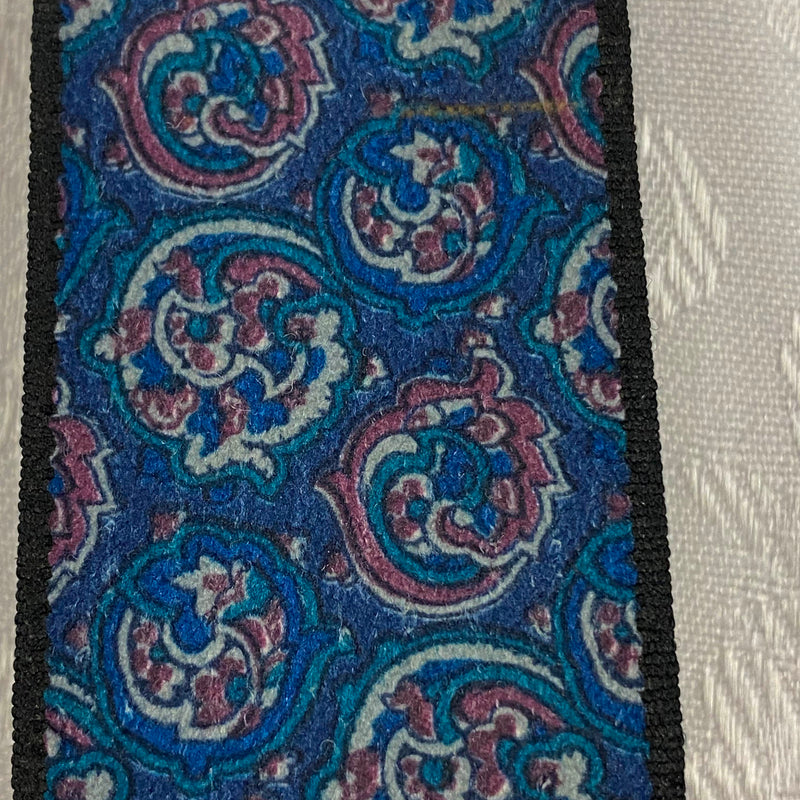 „Detailaufnahme von gemusterten Vintage Hosenträgern mit blauem Paisley-Muster“