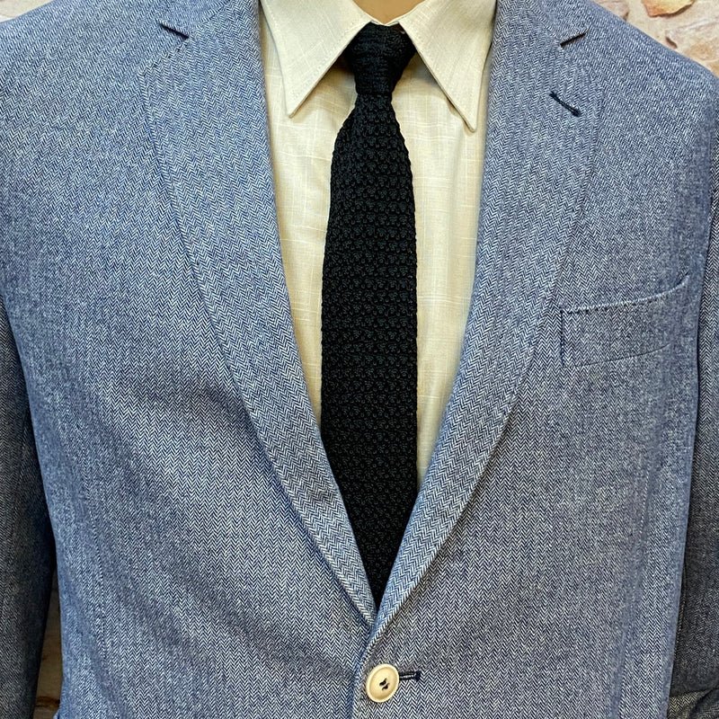 Detailansicht Revers, hellbeiges Hemd und schwarze Strickkrawatte des grauen Slim-Fit-Anzugs