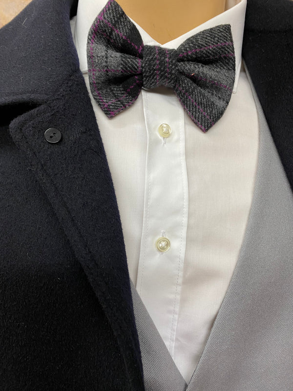 „Detailaufnahme der grauen Handmade-Fliege am weißen Hemd unter schwarzem Mantel – 20er Jahre Stil.“