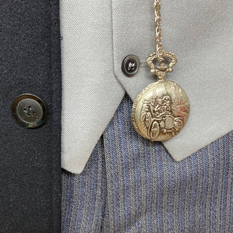 „Detail der silbernen Taschenuhr an der grauen Weste – Deko, nicht im Lieferumfang enthalten.“