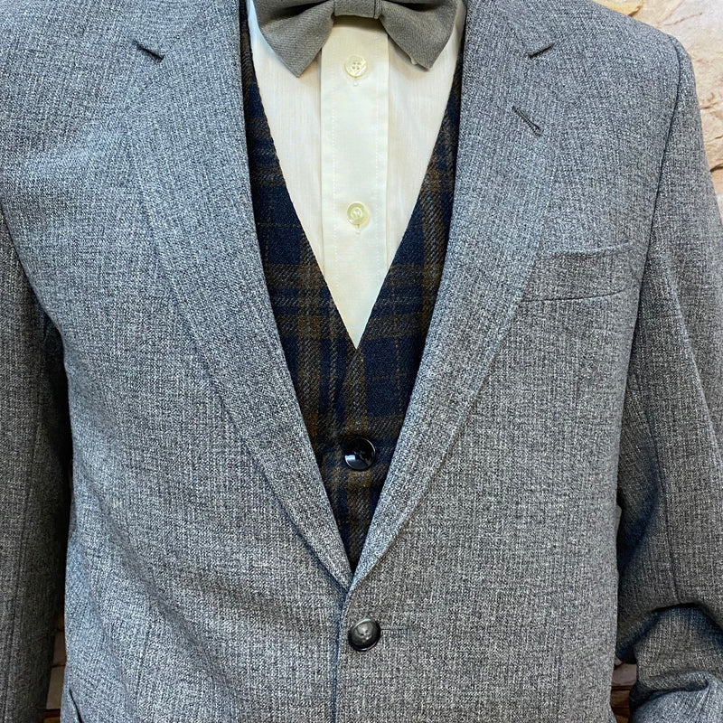 „Nahaufnahme Revers und graue Fliege, weiße Hemdbluse und karierte Weste im 1920er Look“