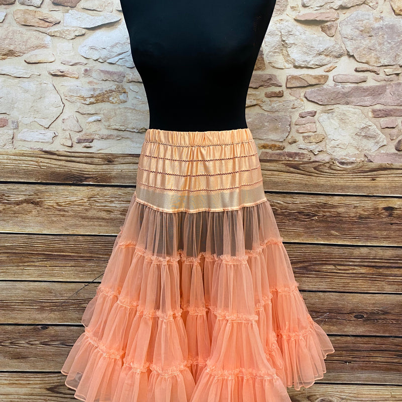 „Apricotfarbener Petticoat in Tellerweite auf schwarzer Schneiderpuppe, weich fallend und füllig, Länge etwa 65 cm.