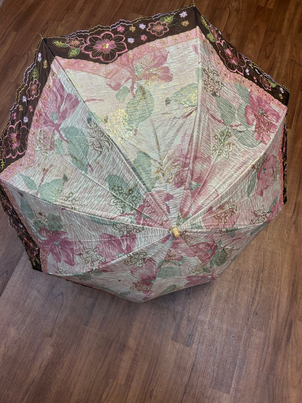 „Geöffneter Vintage-Schirm mit Blumenmuster und besticktem Spitzenrand in Schwarz und Gold“