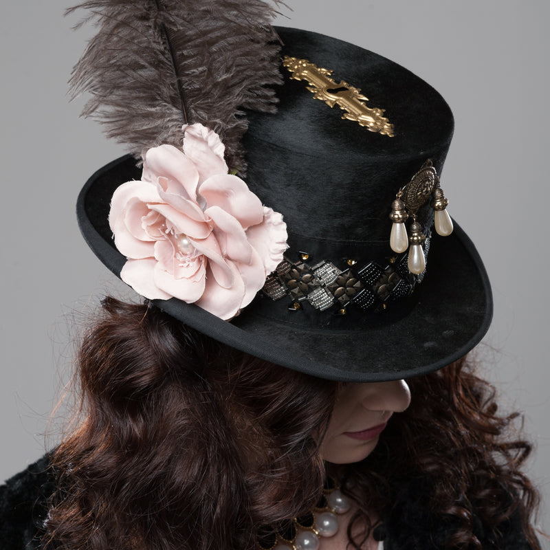 Handveredelter Steampunk-Zylinder Gr. 57 mit Feder, roséfarbener Blüte und messingfarbenen Applikationen.