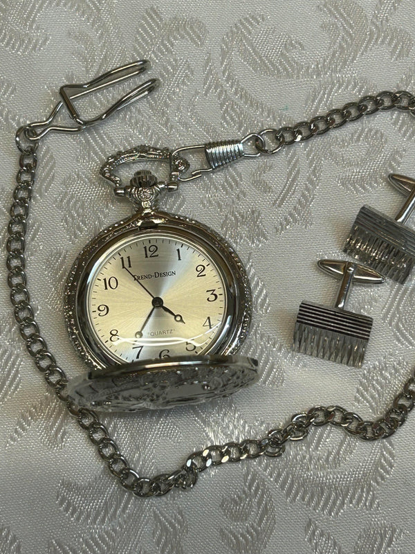 „Set aus Taschenuhr und Manschettenknöpfen auf weißem Stoffhintergrund“