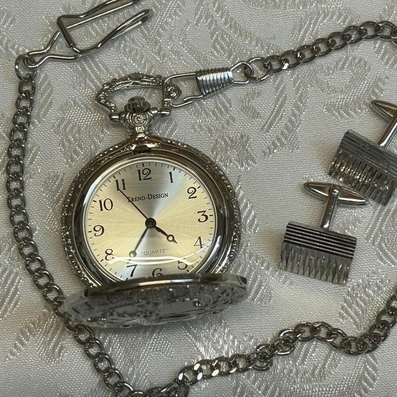 „Set aus Taschenuhr und Manschettenknöpfen auf weißem Stoffhintergrund“