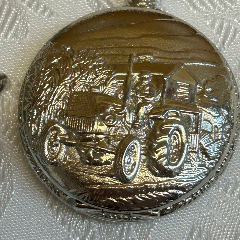 „Detailaufnahme Traktor-Relief auf Taschenuhrdeckel, silberfarben glänzend“
