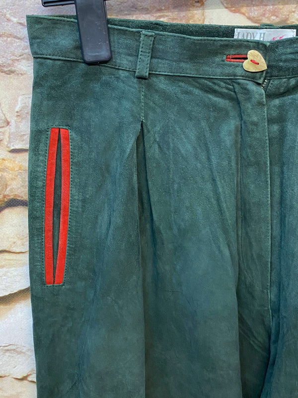 Detail einer dunkelgrünen Damen Lederhose mit rotem Akzent und Herzknopf