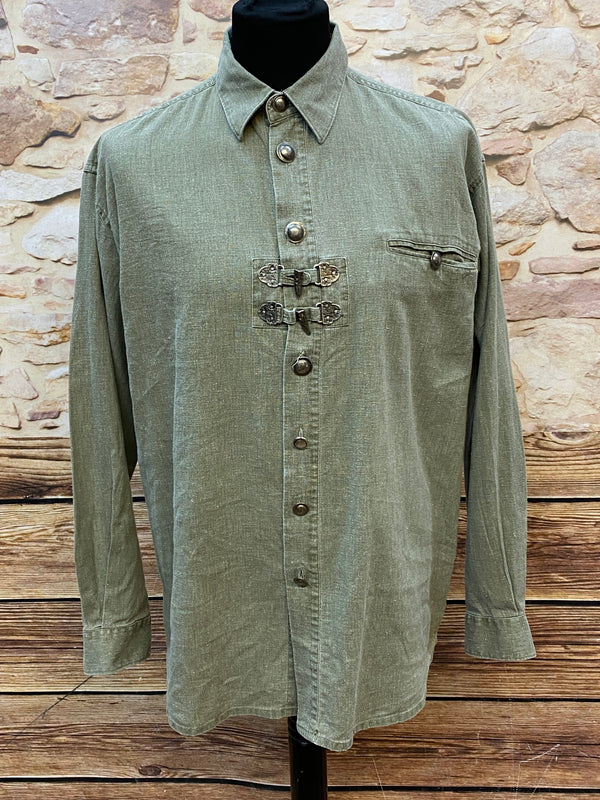 Alttext
„Olivgrünes Trachtenhemd mit Metallschnallen und Brusttasche auf Schneiderpuppe“