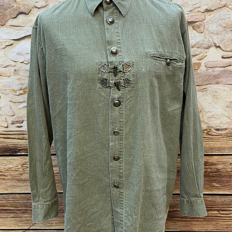 Alttext
„Olivgrünes Trachtenhemd mit Metallschnallen und Brusttasche auf Schneiderpuppe“