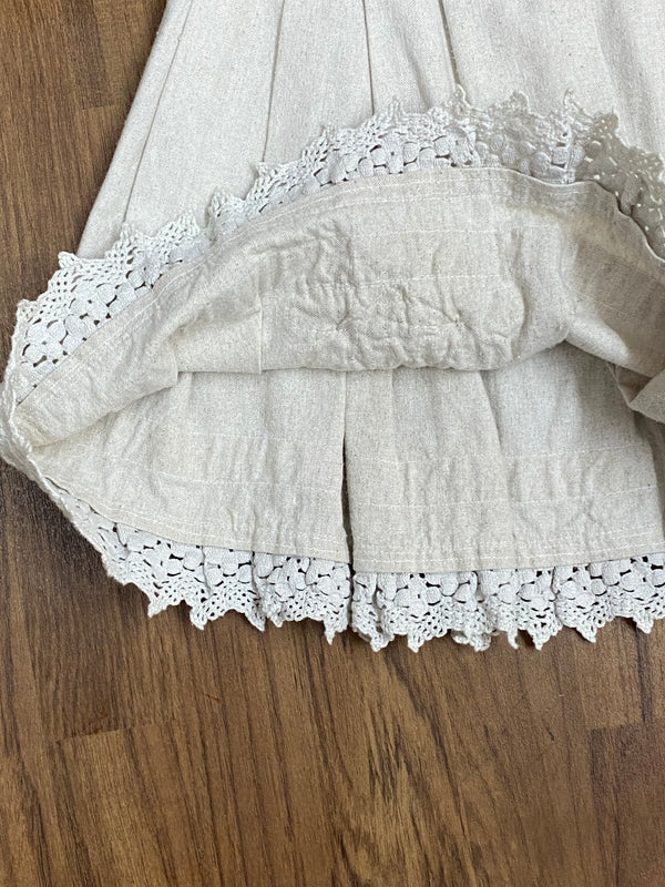 „Detailaufnahme der Klöppelspitze und Trachtenknöpfe am Rocksaum“