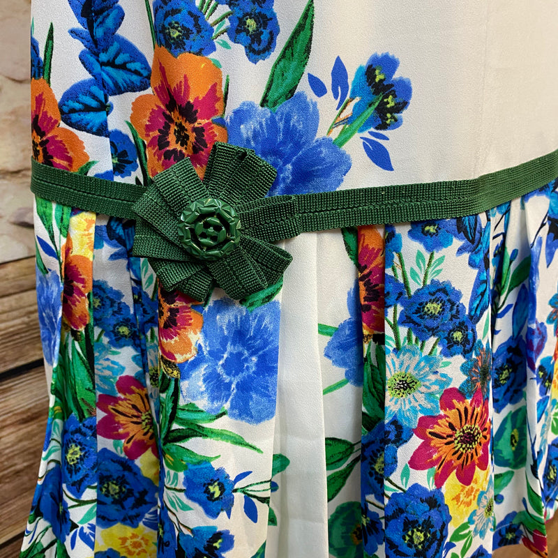 „Buntes 20er Jahre Tageskleid mit tiefer Taille, Blumenmuster und grüner Perlenkette als Vintage Damen Outfit“