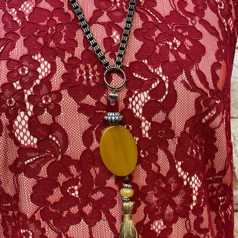 „Detailaufnahme rotes Spitzenkleid mit heller Rüschenbordüre, Stoffblüte und Vintage Kette mit Quaste“